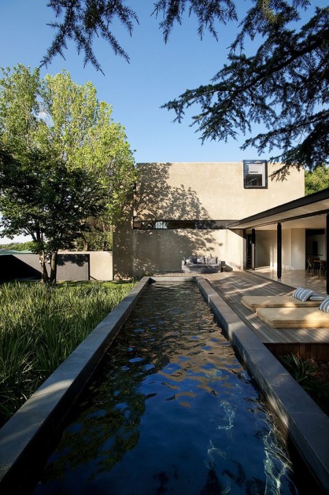 a comfy deck, a long narrow pool and greenery next to it for a relaxing feel