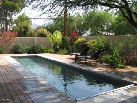 a cozy deck with much greenery and a long narrow pool