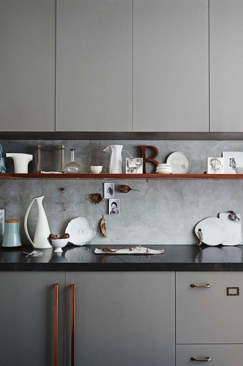 a grey kitchen with a black countertop and a concrete backsplash for a textural look