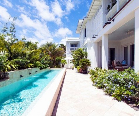 a long and narrow pool with waterfalls and planted and potted greenery around