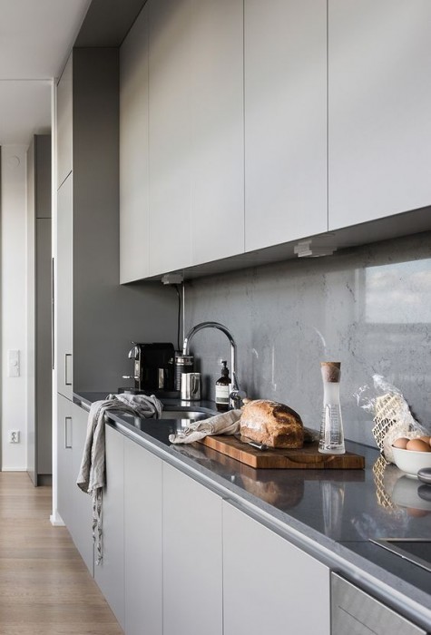 a minimalist light grey kitchen with a concrete backsplash and a glass cover to avoid splashes