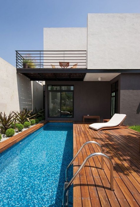 a modern deck with a long and narrow poll clad with mosaic tiles