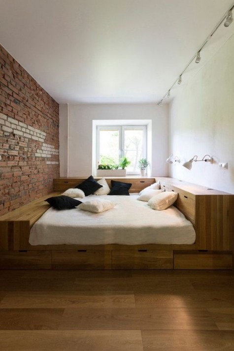 a small bedroom with a podium bed with much built-in storage