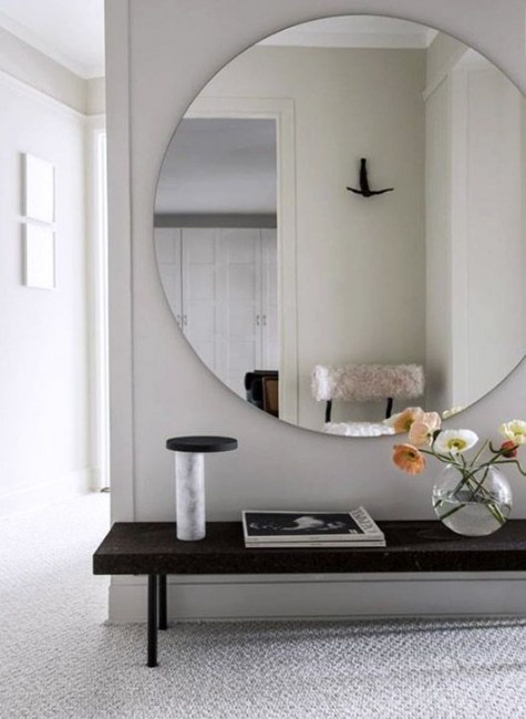 a small entryway with an oversized mirror and a bench