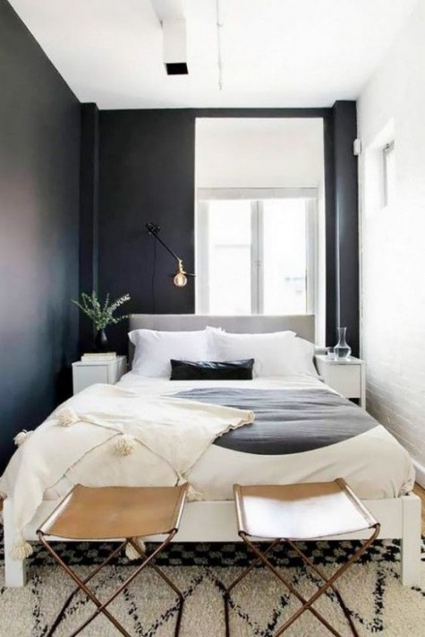a tiny bedroom features only a large bed and very small nightstands plus leather stools for storage