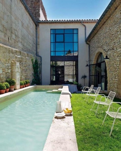 a welcoming backyard with chairs and a long and narrow pool