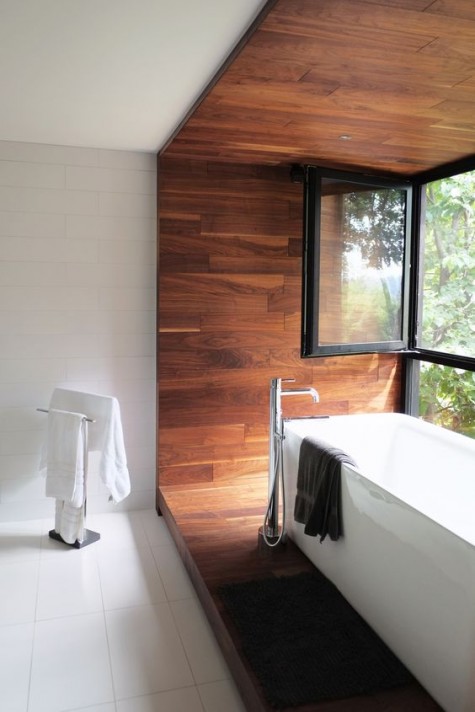 a bathtub placed into a cradle of wood panels and a glazed wall fora gorgeous view