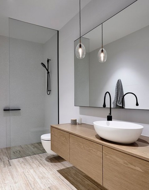 a clean minimalist bathroom with an oversized black framed mirror