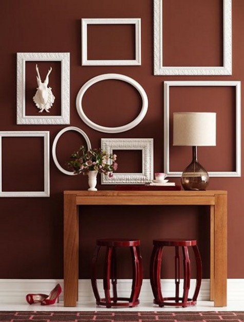 a chic entryway with vintage white frames and red stools