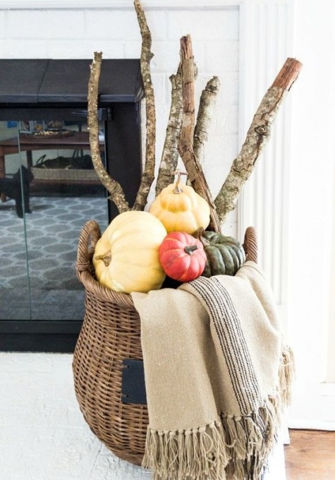 a cool modern fall display with a tall basket, a blanket, branches and colorful pumpkins