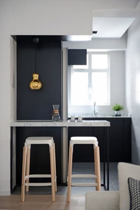 a small and narrow table with tall stools and a pendant lamp