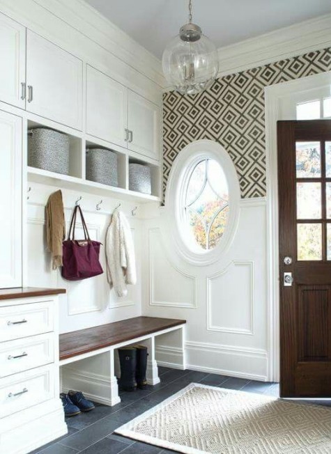 a vintage farmhouse entryway with white wainscoting on the walls and a round window