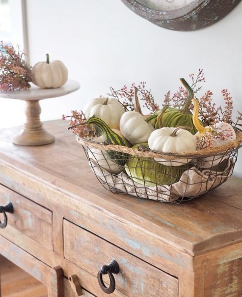 a wire basket with natural and velvet pumpkins and small flowers