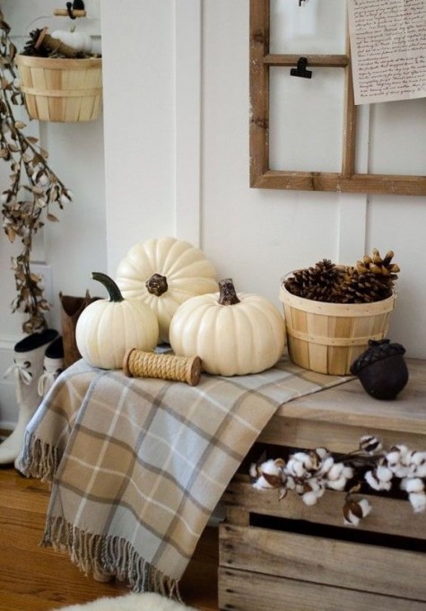 white pumpkins, pinecones in a wooden basket and a checked blanket