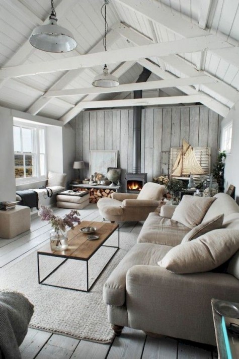 a farmhouse living room done in neutrals, with a weathered wooden wall, a hearth, a firewood storage and some modern furniture