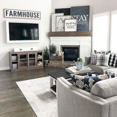 a farmhouse living room done in neutrals, with grey upholstered furniture, a rustic coffee table, a gallery wall on the mantel